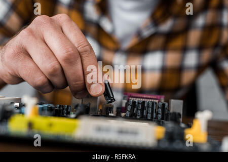 cropped shot of computer engineer taking transistor from motherboard Stock Photo