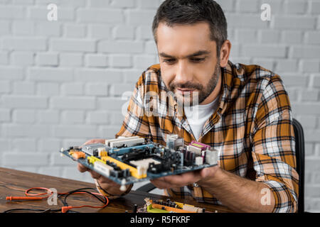 serious handsome computer engineer holding motherboard Stock Photo
