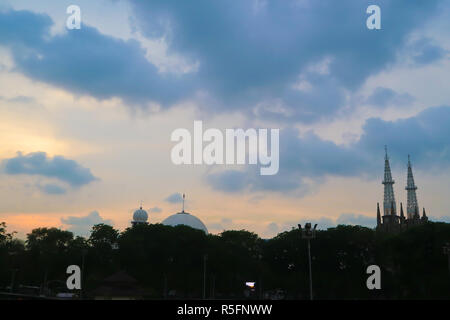 golden moment with silhoutte of spire of Istiqlal Mosque and Kathedral Church in Jakarta Stock Photo