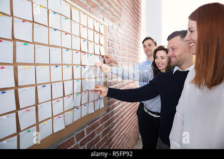 Hands Holding Paper Notes On Corkboard Stock Photo