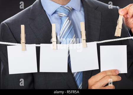 Businessman Pinning Blank Paper On Clothesline Stock Photo