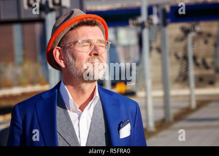 handsome man in his 50s standing at train station and enjoying the sun Stock Photo