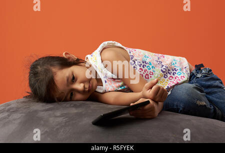 Asian girl sad with phone. 7 years old. Filipina kid. Stock Photo
