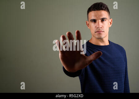 Young handsome man making stop sign gesture against colored background Stock Photo