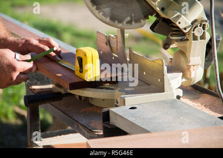 Man measuring a piece of wood for cutting outside in the sun Stock Photo