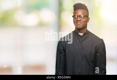 Young african american priest man over isolated background smiling looking side and staring away thinking. Stock Photo