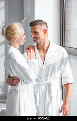 smiling couple standing near window and hugging in spa Stock Photo