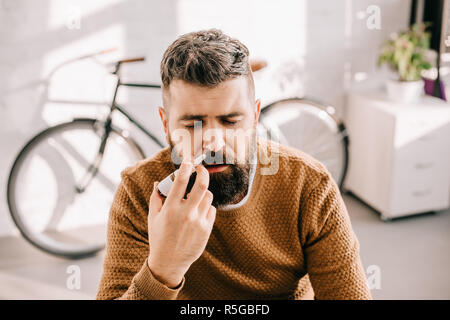 sick man with runny nose using nasal spray Stock Photo