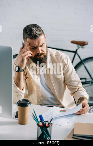 thoughtful businessman sitting at office desk and reading papers Stock Photo