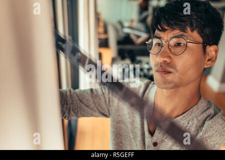 Photographer checking 35mm filmstrip in front of window.  Man selects a frame on old filmstrip. Stock Photo
