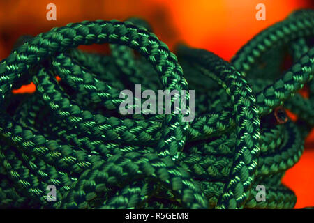 green rope rolled strings in front of orange background, new green rope macro shot for the shipping or health or sports industry Stock Photo