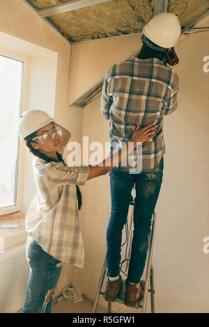 beautiful young woman supporting her husband while he making renovation of home Stock Photo