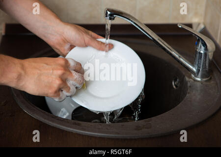 Image of side of man's hands washing transparent mug in sink Stock Photo