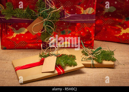 Two Christmas gifts laying in front of two huge Christmas gifts Stock Photo