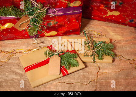 Two Christmas gifts laying in front of two huge Christmas gifts Stock Photo