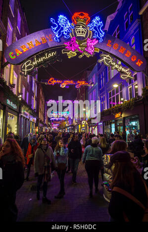 LONDON - NOVEMBER 23, 2018: Black Friday holiday shoppers admire the Bohemian Rhapsody themed Christmas lights decorating historic Carnaby Street. Stock Photo
