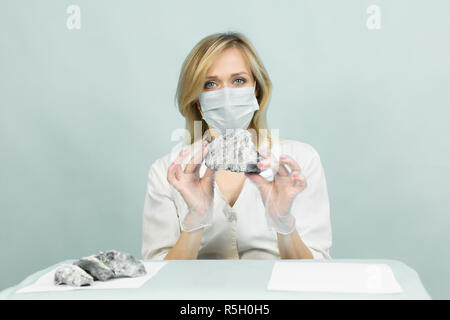 A woman lab worker examines stones for anilization, the content of harmful asbestos. Stock Photo