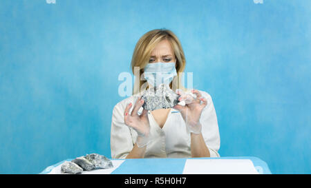 A woman lab worker examines stones for anilization, the content of harmful asbestos. Stock Photo