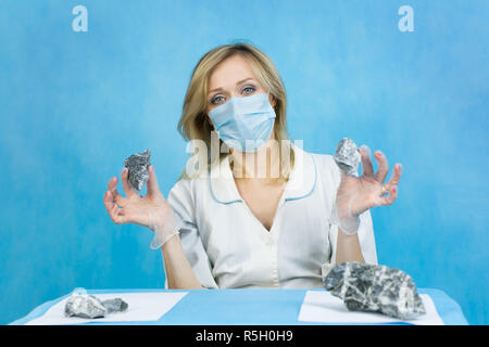 A woman lab worker examines stones for anilization, the content of harmful asbestos. Stock Photo