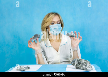 A woman lab worker examines stones for anilization, the content of harmful asbestos. Stock Photo