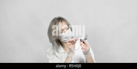 A woman lab worker examines the stones with tweezers takes the fibers of harmful asbestos. Stock Photo