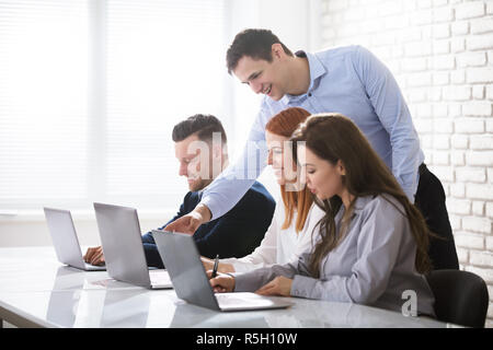 Businessman Standing And Speaking To His Coworkers Stock Photo