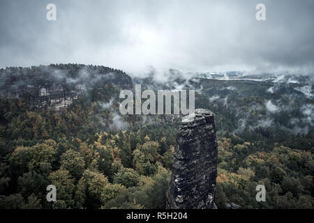 Deadpan dark misty rainy morning landscape with the sand rocky montains in Czech Saxon Switzerland in autumn colors. Stock Photo