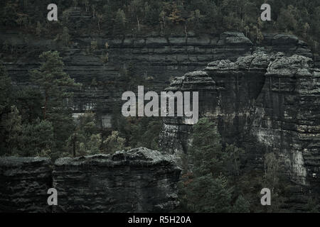 Deadpan dark misty rainy morning landscape with the sand rocky montains in Czech Saxon Switzerland in autumn colors. Stock Photo