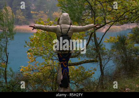 A woman in lake Tsivlos balancing on a tree log, on a rainy day. Stock Photo