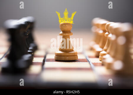 Pawn With King Crown Amidst Chess Pieces Stock Photo