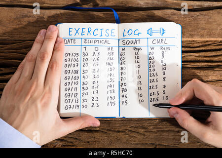 Person Filling Exercise Log On Notebook Stock Photo