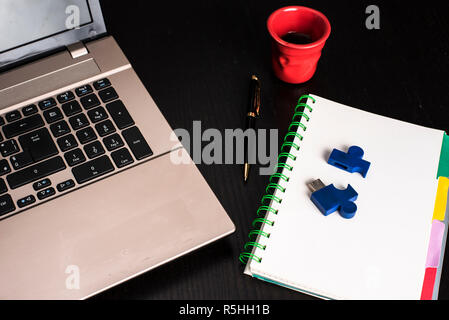 still life with blocknote, labtop, pen and a red cup of coffee over a black office desk. symbol of job Stock Photo