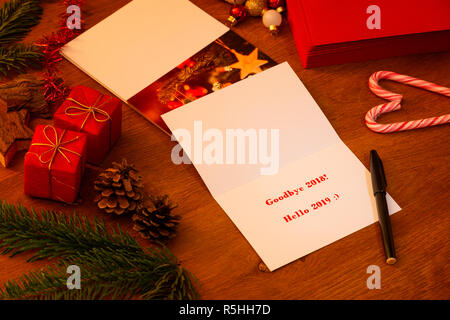 Goodbye 2018 Hello 2019 Christmas and New Years Card, waiting to be signed with a marker. Stack of other cards and envelopes in the background. Stock Photo
