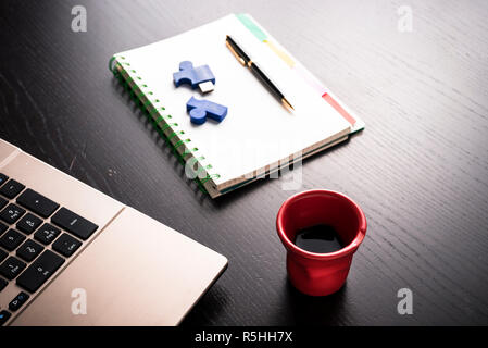 still life with blocknote, labtop, pen and a red cup of coffee over a black office desk. symbol of job Stock Photo