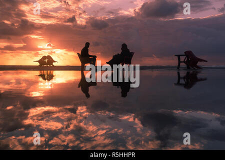 Silhouette photo of couple sitting in deckchairs on beach. Gaza-Palestine Stock Photo