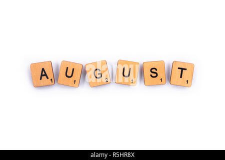 London, UK - July 8th 2018: AUGUST, spelt with wooden letter tiles over a plain white background. Stock Photo