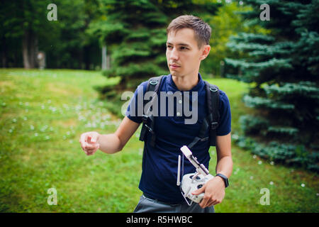 a man who runs a drone for photo or video and manages it using a remote control in his hand Stock Photo