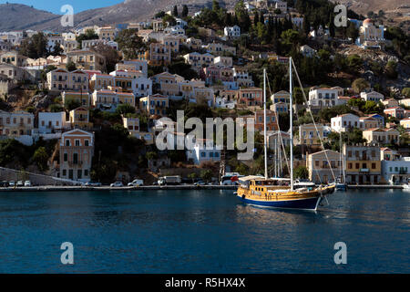 Luxury vintage sailboat anchored in a blue lagoon at Symi island, Greece, on a bright sunny day. Stock Photo