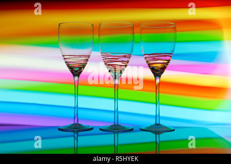 Three wine glass / glasses  with colourful light painting behind them