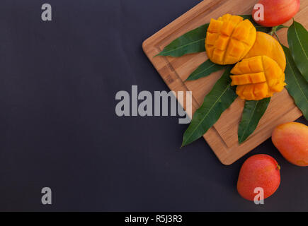 Mango fruit and mango cubes on the wooden cutting board. Tropical fruit concept with a huge amount of negative space for text. Stock Photo