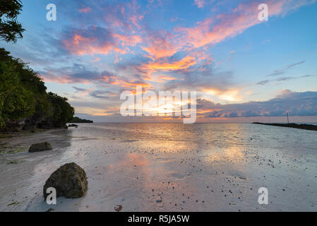 Sunset dramatic sky on tropical desert beach, coral reef reflection no people, travel destination, Indonesia Wakatobi Stock Photo