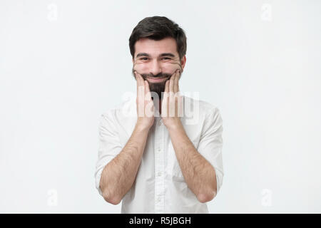 Bored hispanic man with beard holding hand on cheek , looking tired and sick. Stock Photo