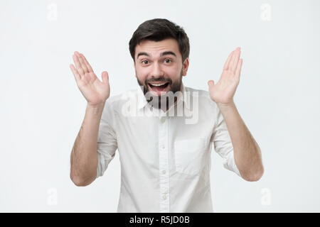 Enthusiastic happy and excited young handsome man raising hands in joy. Stock Photo
