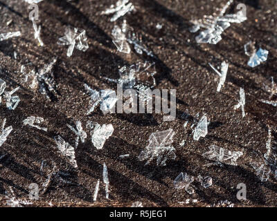 Frost crystals forming beautiful  geometrical shapes on wood surface against black background Stock Photo