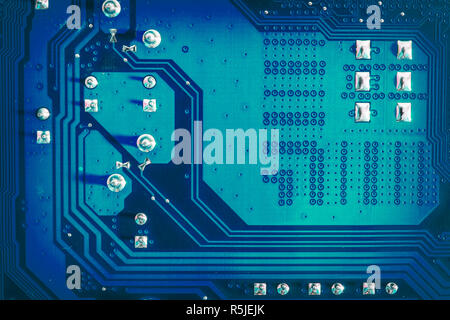 Blue side of motherboard circuit with soldered contacts and texture. High-tech abstract background with digital and computer technology concept Stock Photo