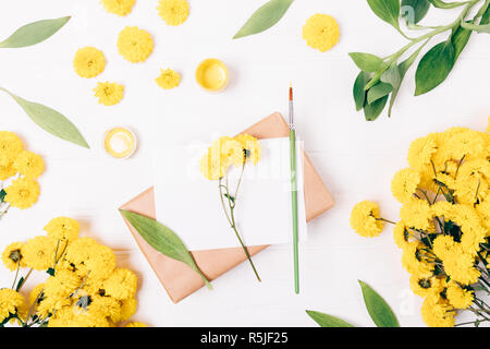 Floral flat lay composition of gouache paint and brush next to greeting card and gift box on white background, view from above. Stock Photo