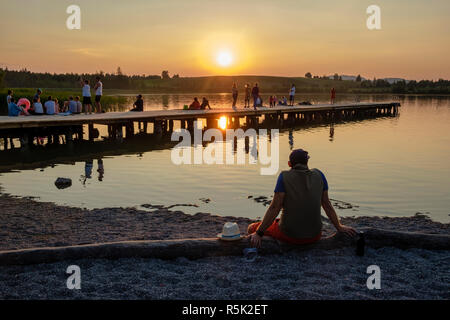 Holidaymakers watch the sun set over Bannwaldsee, Schwangau, Bavaria, Germany Stock Photo