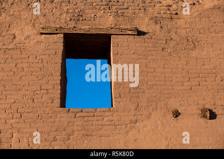 Window, blue sky, and rustic wood beams in the adobe wall of the ruins of an old Spanish mission church at Pecos National Historic Park in New Mexico Stock Photo