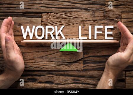 Hands Covering Balance Between Life And Work On Seesaw Stock Photo