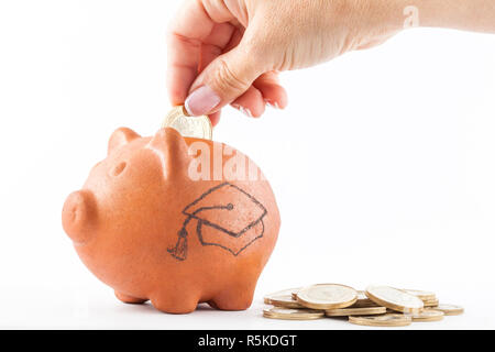 Close up of a woman saving money into a traditional clay piggy bank to study Stock Photo